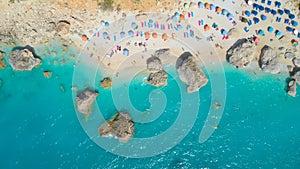AERIAL: Tourists relaxing on the lounge chairs and swimming in the turquoise sea