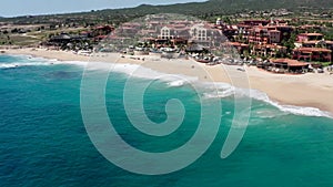 Aerial, tracking, tilting towards waves, hitting the Sheraton beach, in Cabo