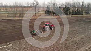 Aerial: tractor cultivates land on farmland near the highway