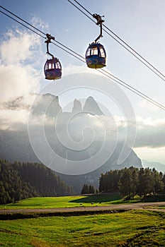 Aerial Tram Cable Car going up, during sunset, with green grass