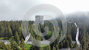 Aerial of treetop walk Pohorje surrounded by a dense forest captured in a foggy weather