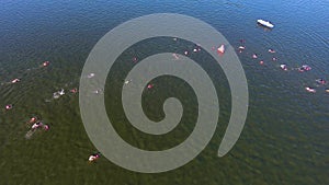 Aerial of triathlon participants bypass buoy on water with lifeboat nearby