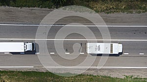 Aerial. Two little trucks driving by the highway. Top view