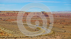 AERIAL: Two trucks drive along the empty highway winding through the Utah desert