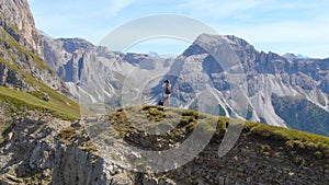 AERIAL: Unrecognizable female photographer taking photos of the rocky mountains.