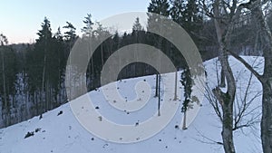 AERIAL. Unveiling shot surounded by trees in cold winter forest in Naujoji Vilnia on snowy Rokantsikiu the castle`s site hill