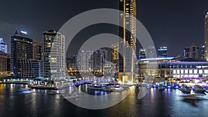 Aerial vew of Dubai Marina with shoping mall, restaurants, towers and yachts night timelapse, United Arab Emirates.