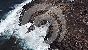 Aerial video of blue sea waves hitting the rocks