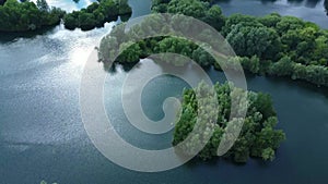 Aerial video of drone flying backwards over lake showing nature and industrial areas