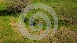 Aerial video of man walking in picturesque valley on green grass towards a river. Drone tracking shot of backpacker