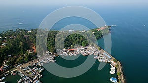 Aerial video of Mirissa harbor with vibrant fishing boats, fisherman busy at work on vessels. Clear blue ocean surrounds