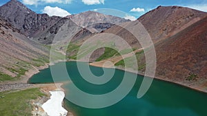 Aerial video of Mountain Spirits Lake in Altai mountains. Herd of horses hides from horseflies on a snowfield