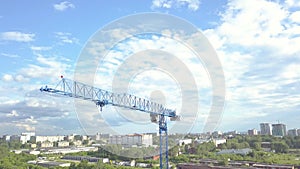 Aerial video of a raised construction crane against the blue sky and white clouds on a summer day at the building site raises the