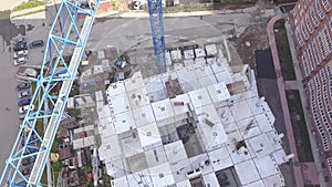 Aerial video of a raised construction crane against the blue sky and white clouds on a summer day at the building site raises the