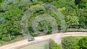 Aerial view of 4x4 car on dusty road in the green valley in tropical country.