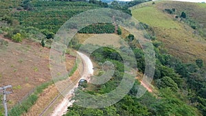 Aerial view of 4x4 car on dusty road in the green valley in tropical country.