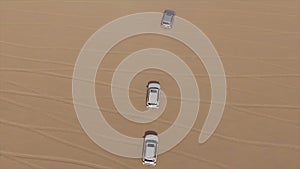 Aerial view of 4x4 off road land vehicle taking tourists on desert dune bashing safari in Dubai, UAE. AERIAL: cars in a