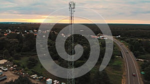 Aerial view of the 5G antenna rising above the road and fields with trees. Country side.