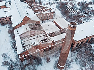 Aerial view of abandoned and ruined red brick factory in snowy winter landscape