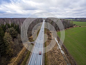 Aerial view from above of country road through the forest in spring morning