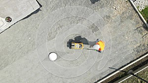 Aerial view above a man tamping foundation with vibratory plate