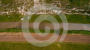 Aerial view of an abrupt valley leading towards a river next to a road on the edge of a plain