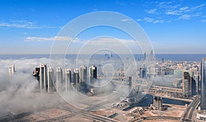Aerial view of Abu Dhabi city skyline, famous towers and skyscrapers surrounded by fog clouds in the morning