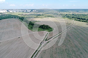 Aerial view on agricultural field with rural road across