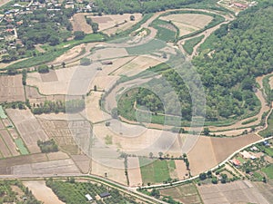 Aerial view of agricultural fields, river, mountains, and land have seen through the airplane window