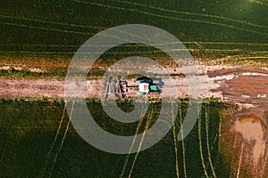 Aerial view of agricultural tractor with tiller attached on dirt road driving to the field, drone pov