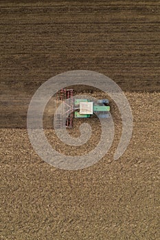 Aerial view of agricultural tractor tilling and harrowing ploughed field, directly above drone pov