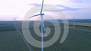 Aerial view of air turbines in a stopped position in a field, near the coast