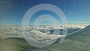 Aerial view from aircraft window on big aircraft wing fly above fluffy white clouds
