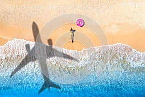 Aerial view of airplane shadow, woman, swim ring, beach, sea