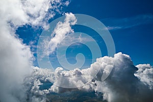 Aerial view from airplane window at high altitude of earth covered with puffy cumulus clouds forming before rainstorm