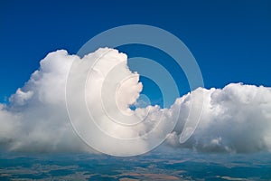 Aerial view from airplane window at high altitude of earth covered with puffy cumulus clouds forming before rainstorm