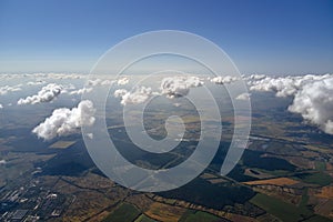 Aerial view from airplane window at high altitude of earth covered with puffy cumulus clouds forming before rainstorm