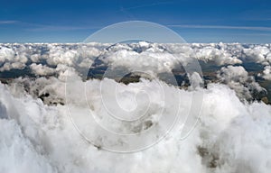 Aerial view from airplane window at high altitude of earth covered with puffy cumulus clouds forming before rainstorm