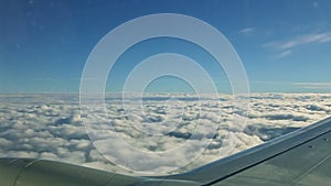 Aerial view from airplane window on large aircraft wing fly above fluffy white clouds