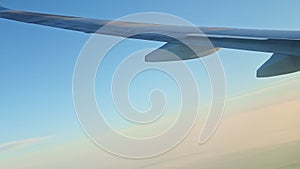 Aerial view from airplane window on steel wing fly against blue sky with white fog