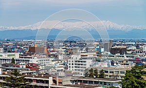 Aerial view of Aizu-Wakamatsu town and snowy mountain behind.