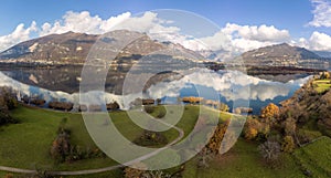 Aerial view of an alpine lake and the surrounding mountains and vegetations reflected