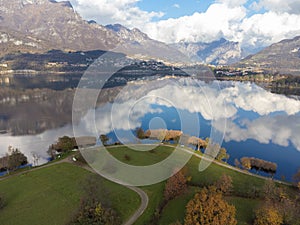 Aerial view of an alpine lake and the surrounding mountains and vegetations reflected