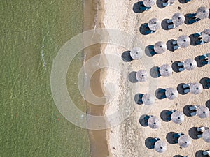 Aerial view of an amazing empty sand beach with straw beach umbrellas and turquoise clear water. Bulgaria Black Sea
