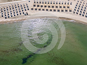 Aerial view of an amazing empty sand beach with straw beach umbrellas and turquoise clear water. Bulgaria Black Sea