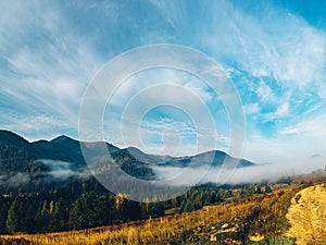 Aerial view amazing over of the Carpathian Mountains or Carpathians with Beautiful autumn landscape , sunrise, blue sky with white