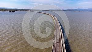 Aerial view of an amazing travel train parked on a floating railway bridge over the water of the lake in Pa Sak Jolasid dam with b