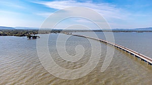 Aerial view of an amazing travel train parked on a floating railway bridge over the water of the lake in Pa Sak Jolasid dam with b