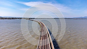 Aerial view of an amazing travel train parked on a floating railway bridge over the water of the lake in Pa Sak Jolasid dam with b