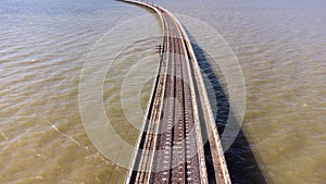 Aerial view of an amazing travel train parked on a floating railway bridge over the water of the lake in Pa Sak Jolasid dam with b